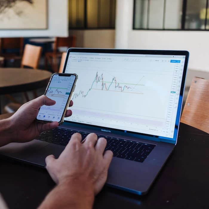 Homme sur son téléphone et son ordinateur regardant des courbes de données
