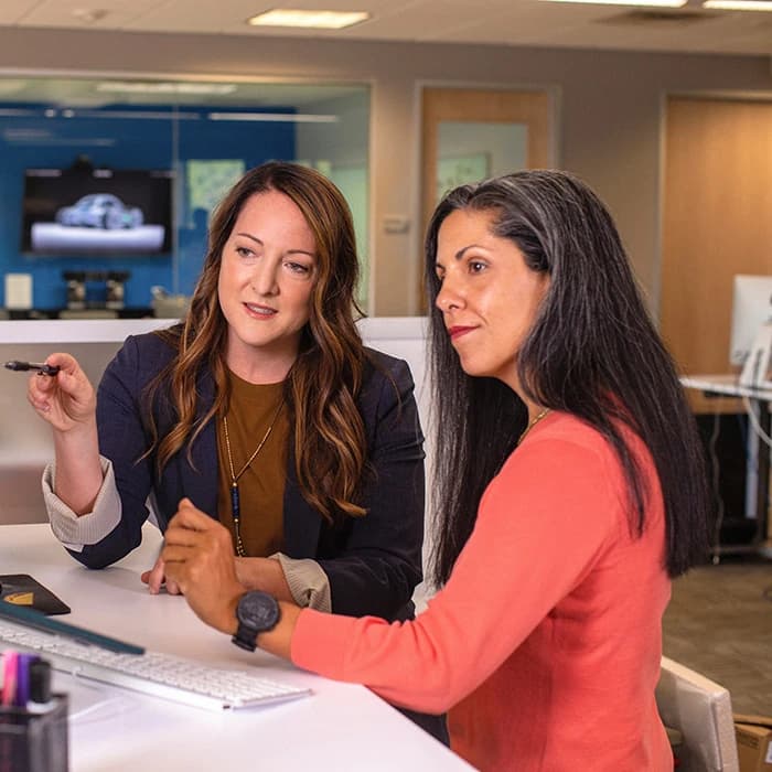 Une femme qui montre quelque chose à une autre femme sur un ordinateur